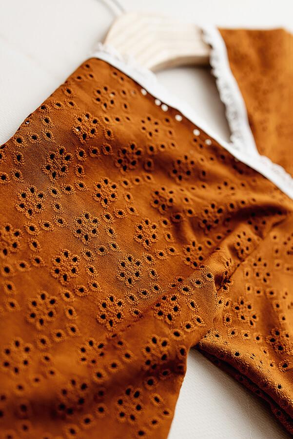 This is a product picture of our BOHO Brocant Cognac. The romper is made of Embrodery Lace and has a BOHO top with long wide sleeves. The neckline is finished with lace.