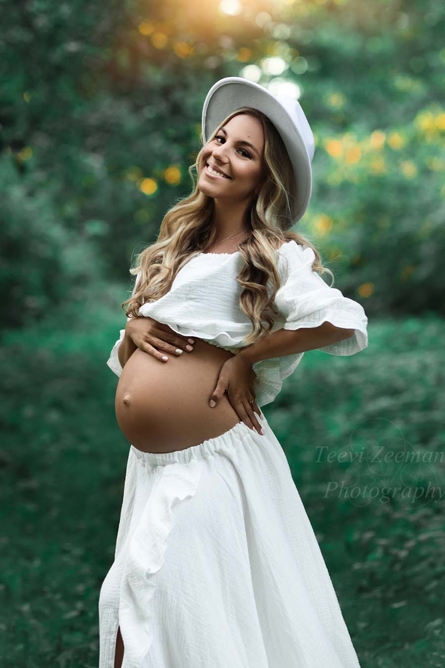 Blond model poses outside wearing an off white bohemian set with a hat to match the look.