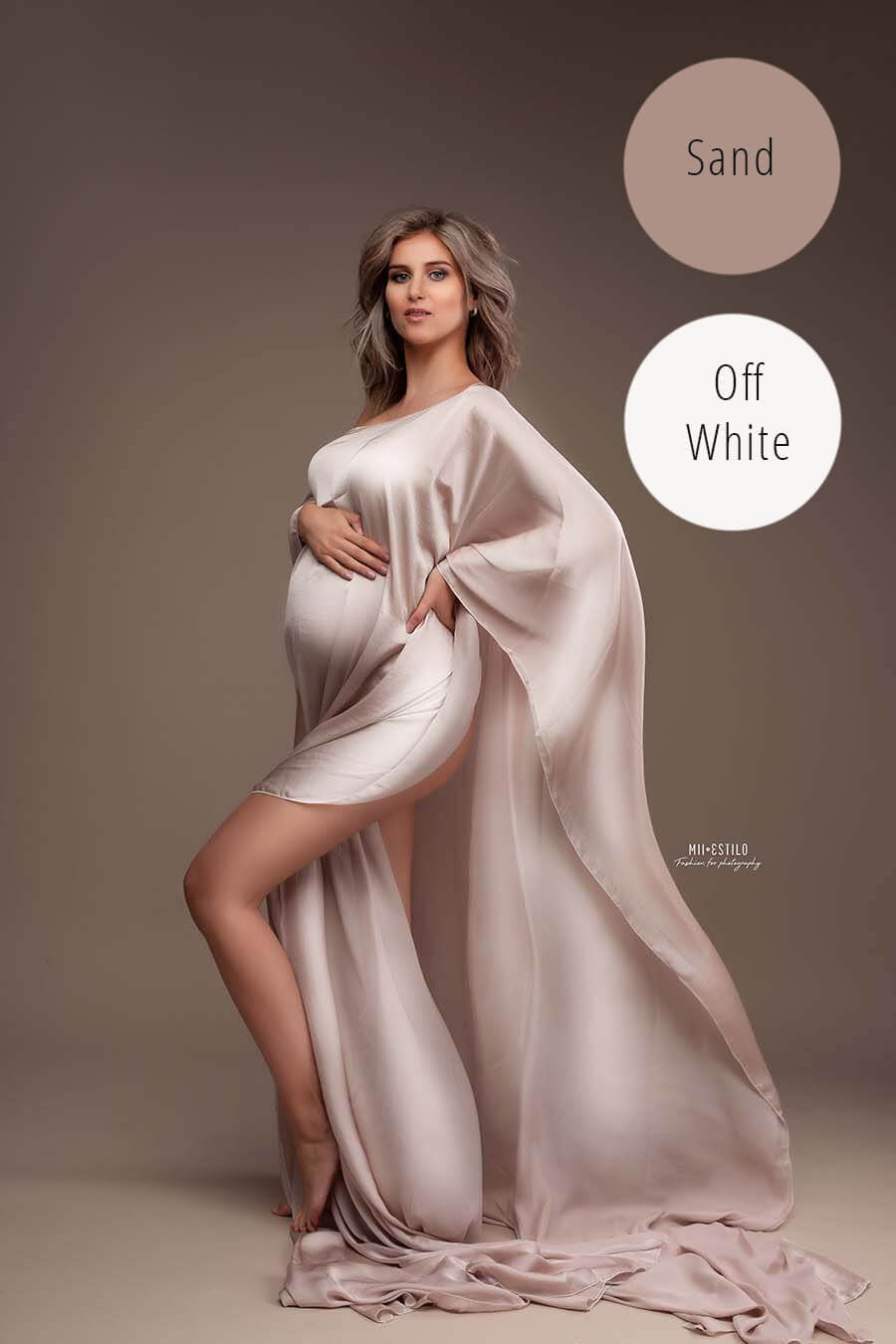 pregnant model poses in a studio wearing a silky cape in sand color.
