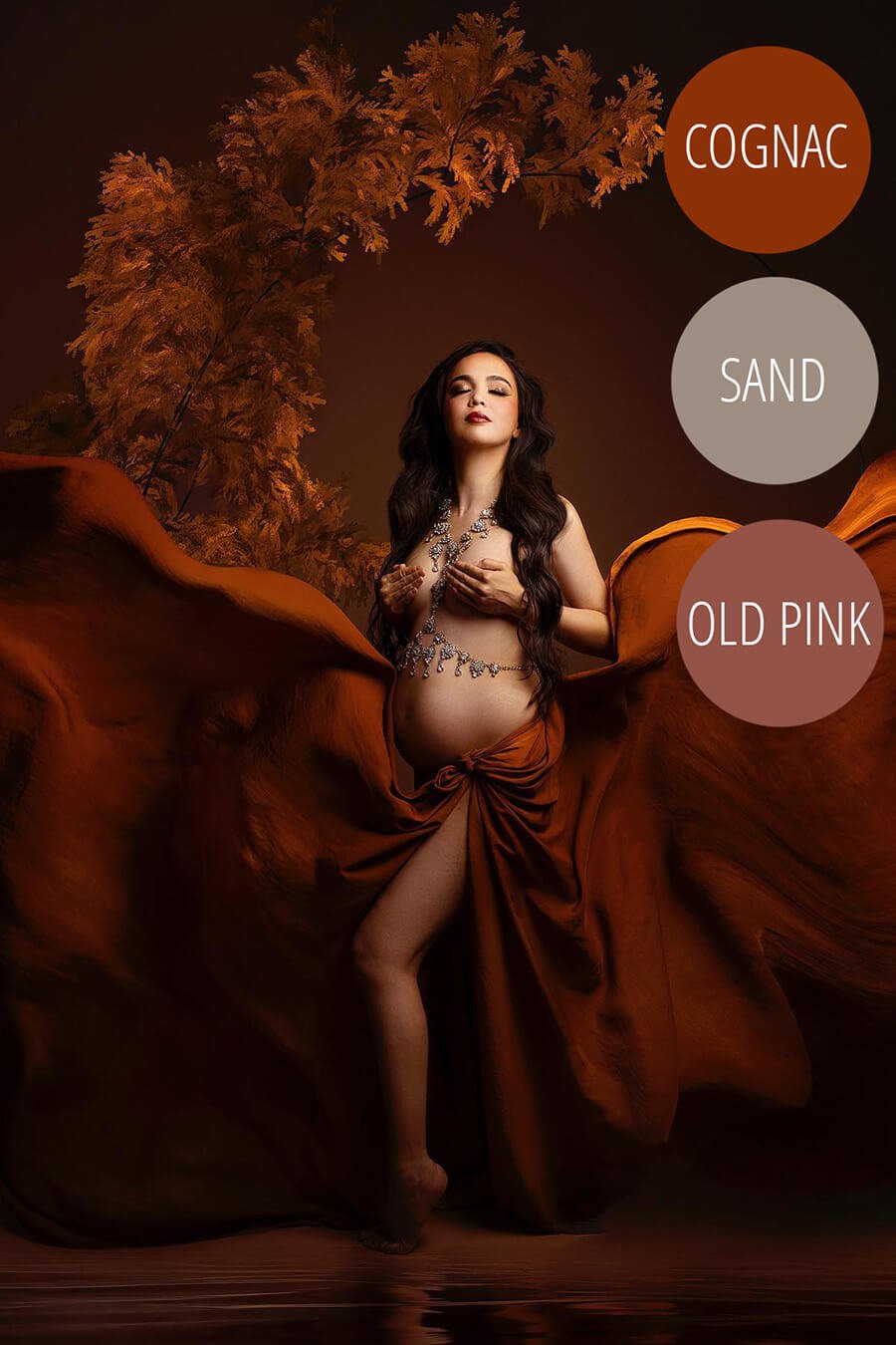 brunette model poses in a studio covering her breasts and with a flowy scarf in cognac color tied as a long flowy skirt.