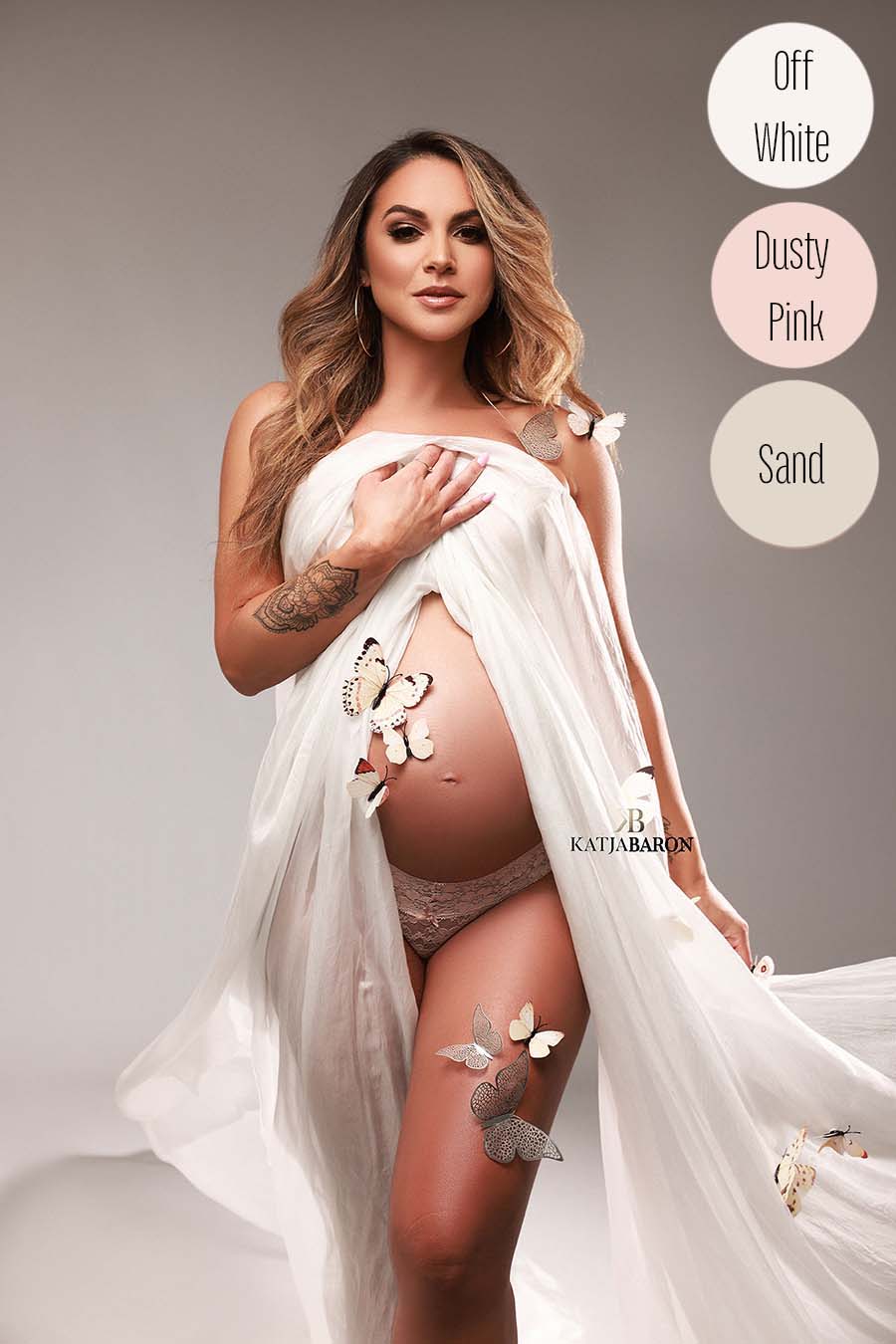 blond pregnant model poses covering her chest area with an off white silky scarf. her belly is uncovered and the model has butterflies all over her.