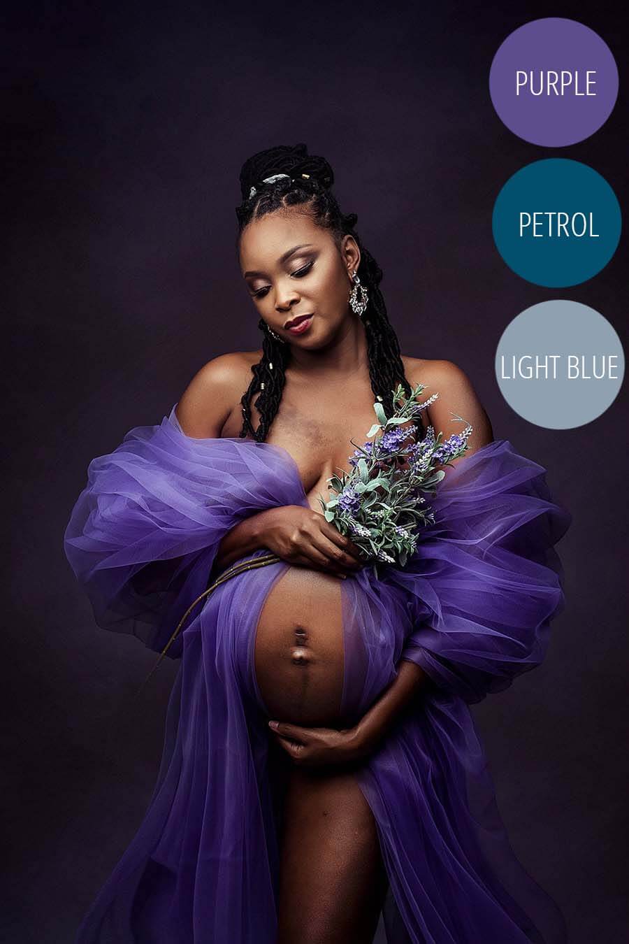 Pregnant model poses wearing a tulle purple piece of fabric around her arms and covering her chest and a lavender bouquet. her eyes are closed and she holds her bump during the close up. 