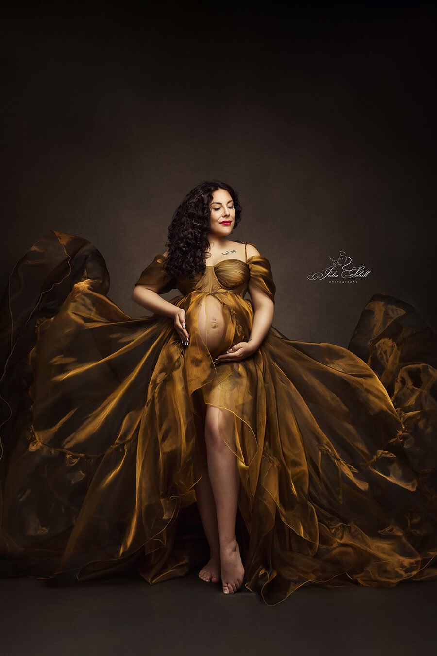 brunette model poses in a studio wearing an organza dress in ocre color.