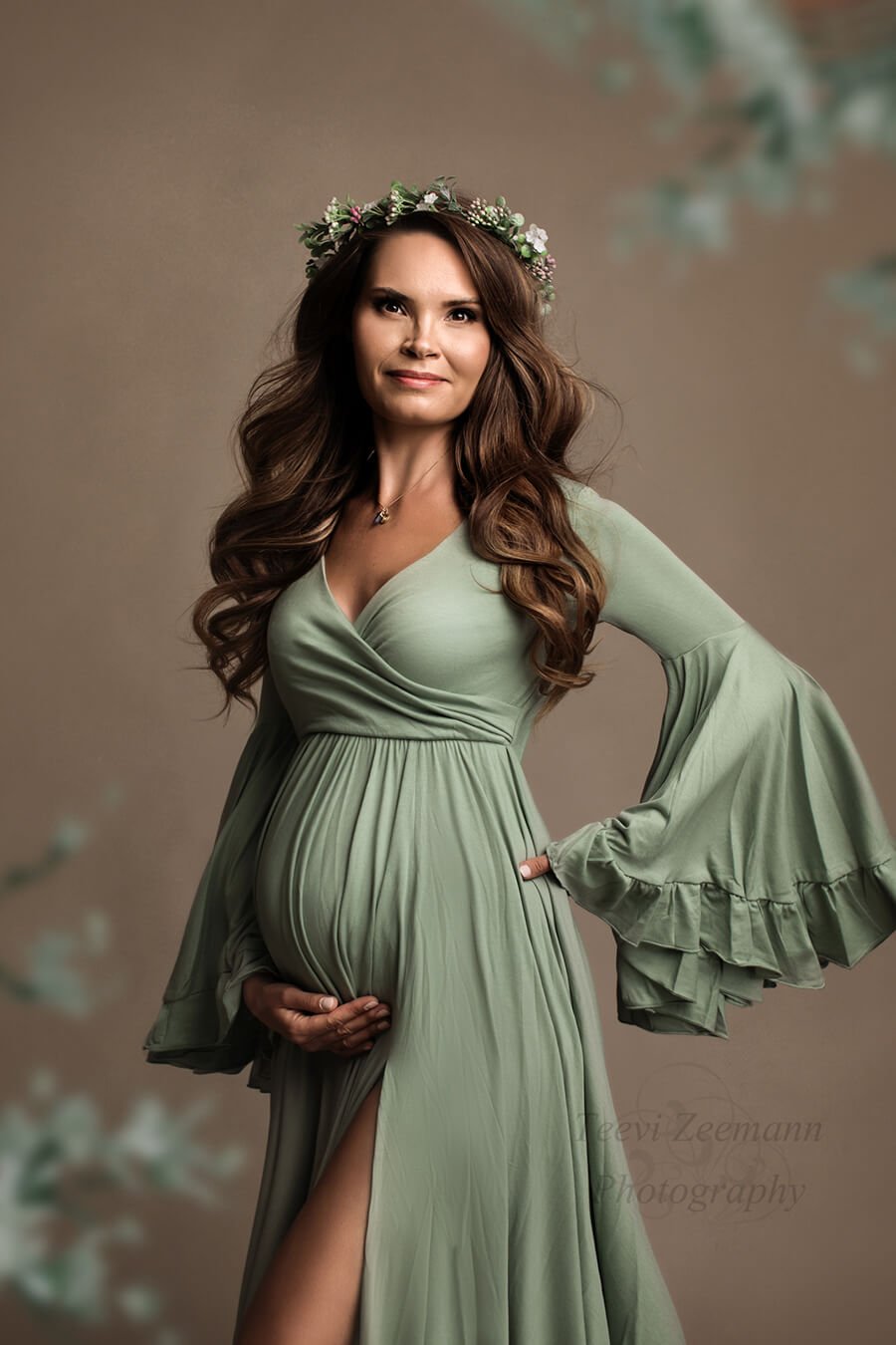 Dark blond pregnant model poses in a studio during a maternity photoshoot wearing a jersey dress designed by Mii-Estilo. The dress features a sweetheart top and bell sleeves. The dress has a split on the side where you can see a bit of the model&