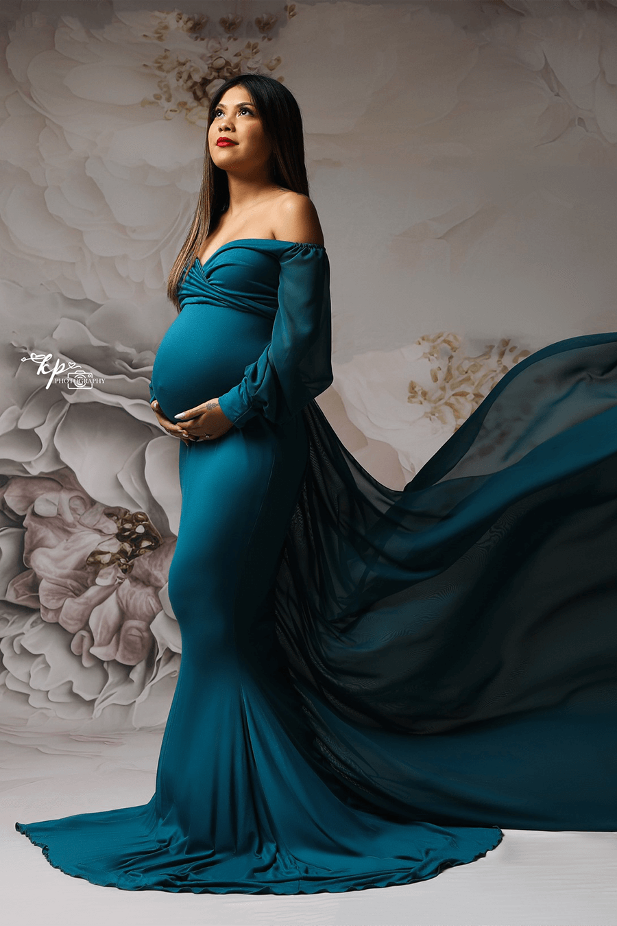 model poses in a studio wearing a petrol long dress with long chiffon sleeves.