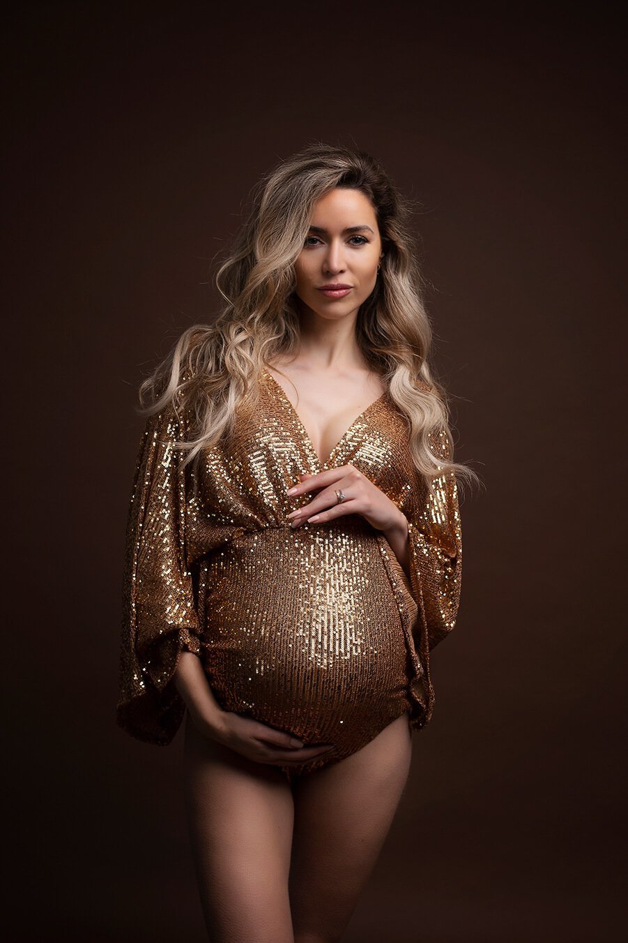 A maternity bodysuit in the color gold. She has long blonde hair. 
