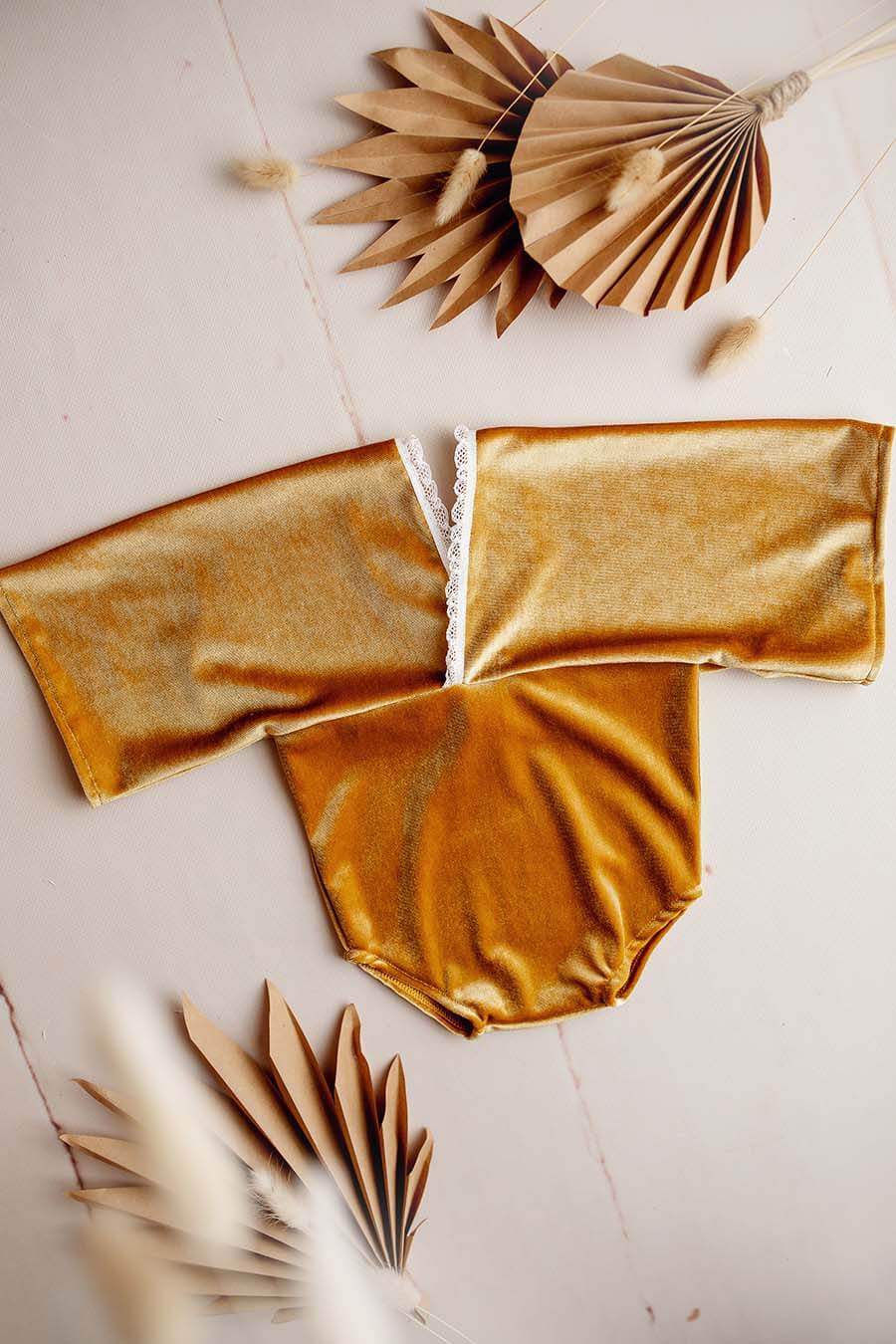 This is a product photo from a baby romper. The romper has a velours fabric and is in the color amber.