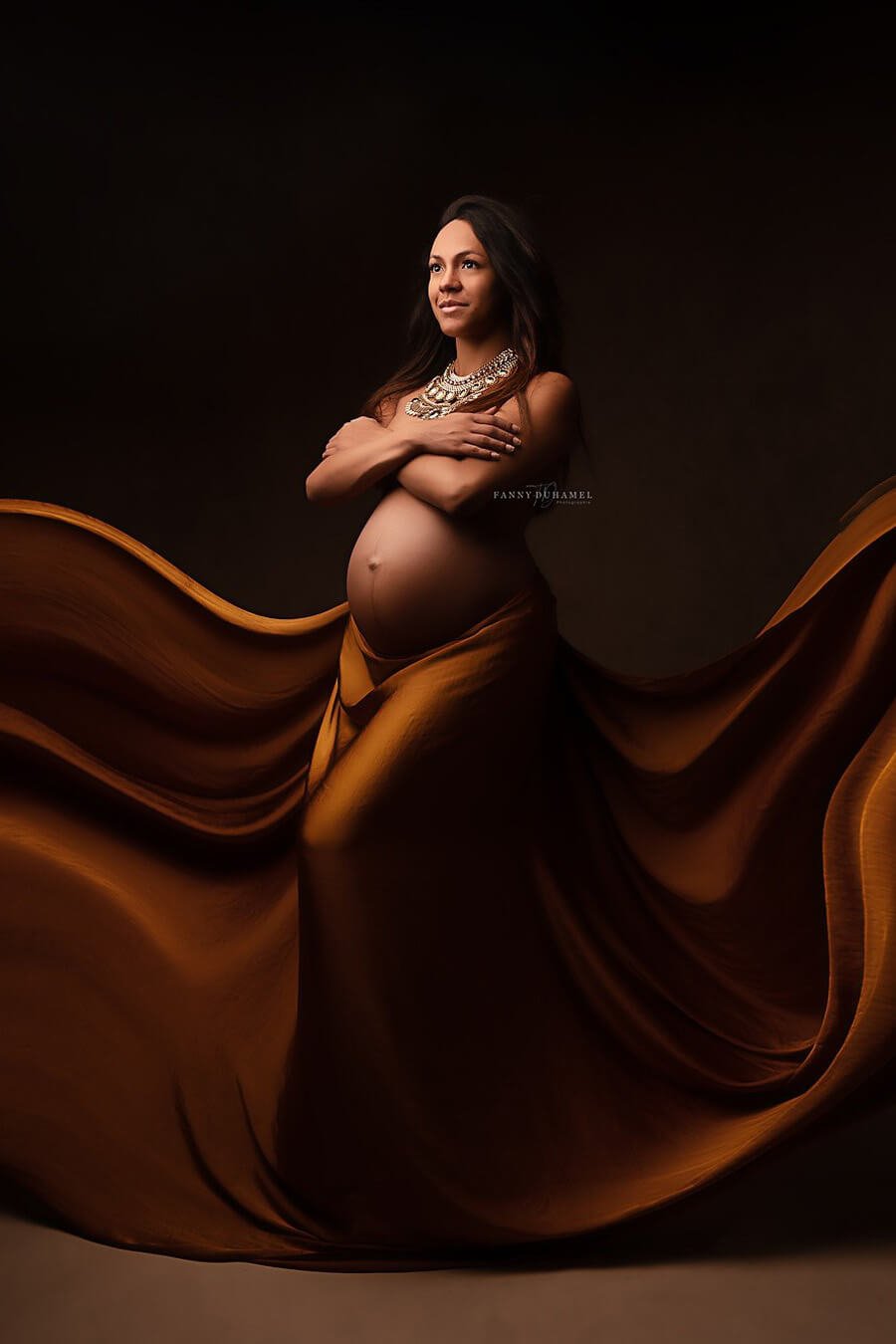 brunette model poses in a studio wearing a silky scarf in cognac as a skirt.