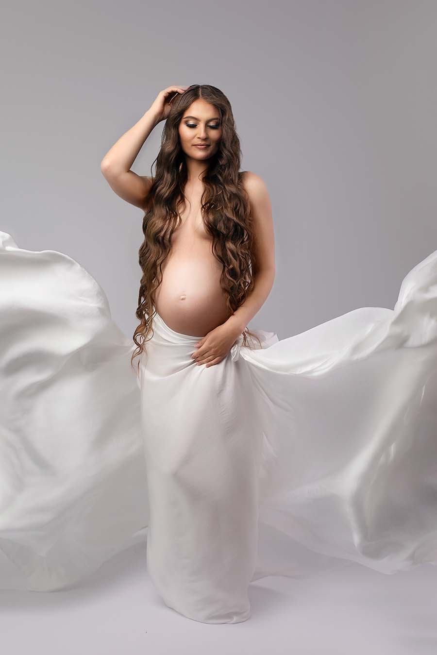 model with long hair poses with her eyes closed. she has a scarf in off white tied on her waist.