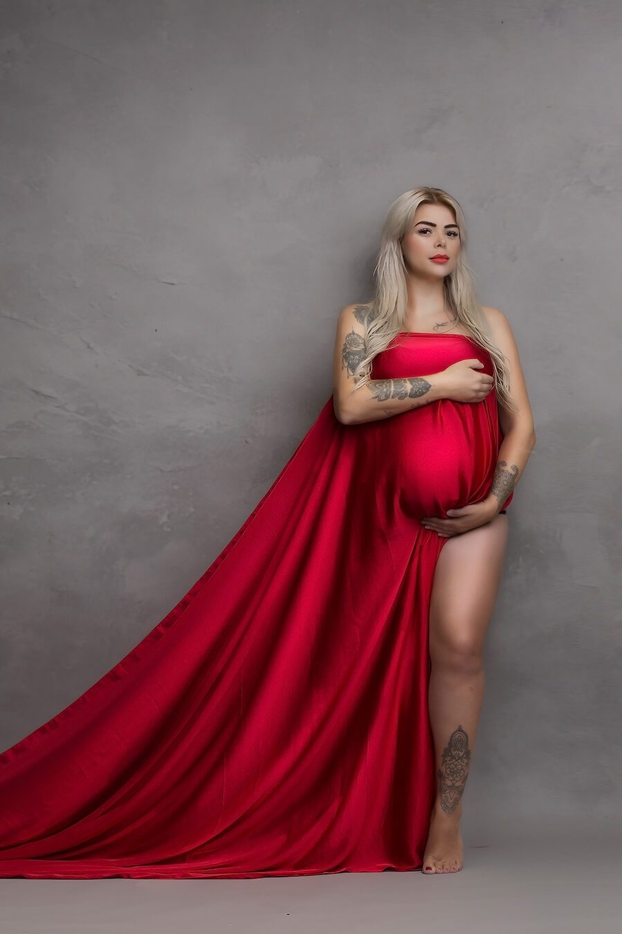 Blond model covers her breasts and belly with a long red silky scarf.