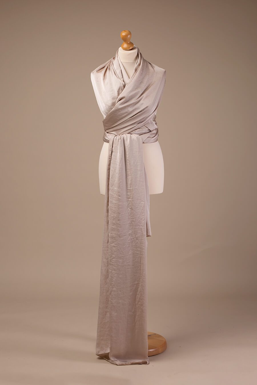 Picture of a draping shimmery piece of fabric in sand color displayed in the studio.