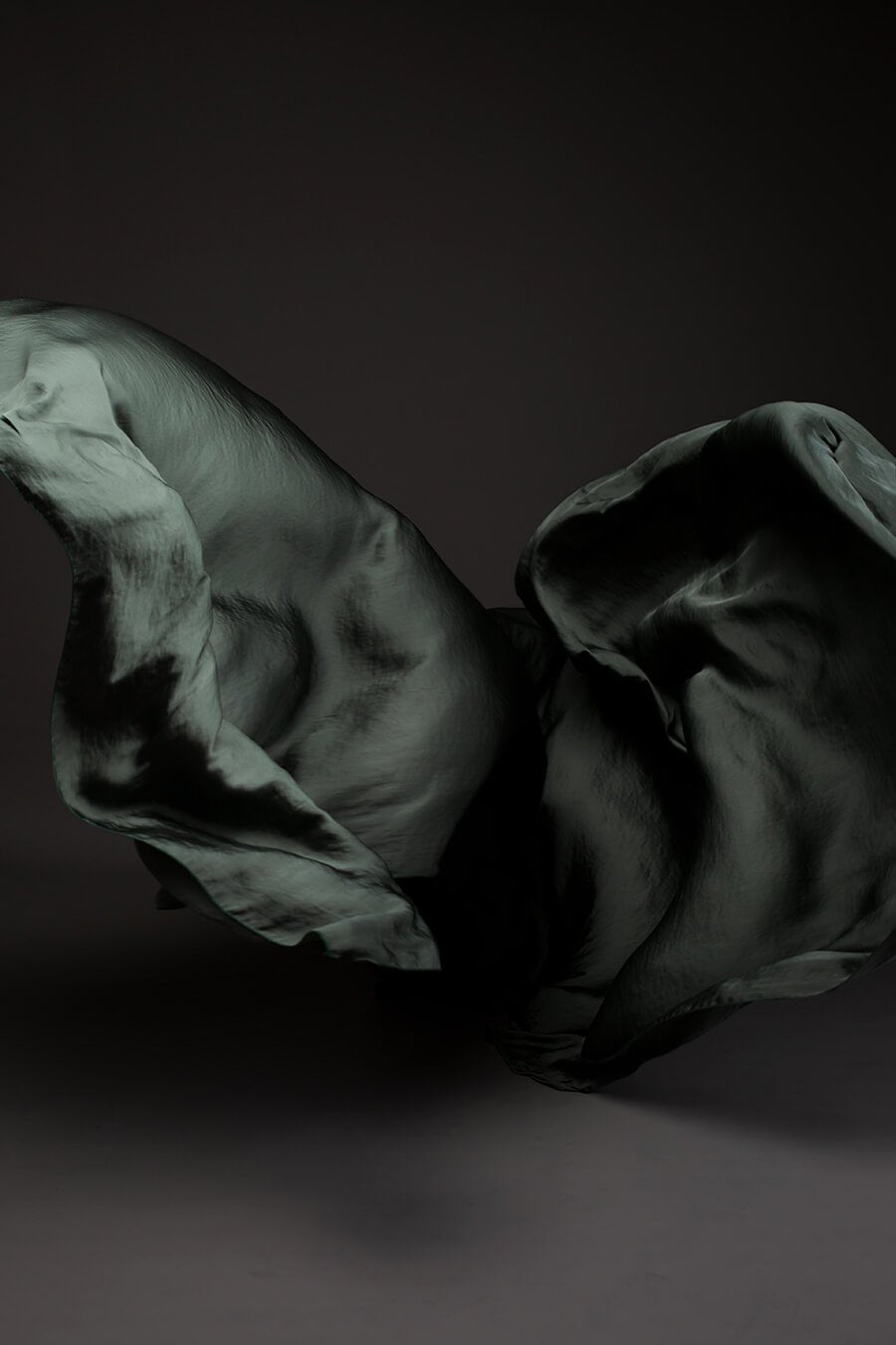 Photo taken on a studio and shows only the mii-estilo silky scarf in slategrey color. The photo shows the scarf flying in front of the camera with playful movements.