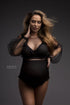 The model is a pregnant woman with blonde hair. She is wearing an black bodysuit with long sleeves. The sleeves are sheer and the top is made of a lace fabric. The bodysuit is very stylish. 