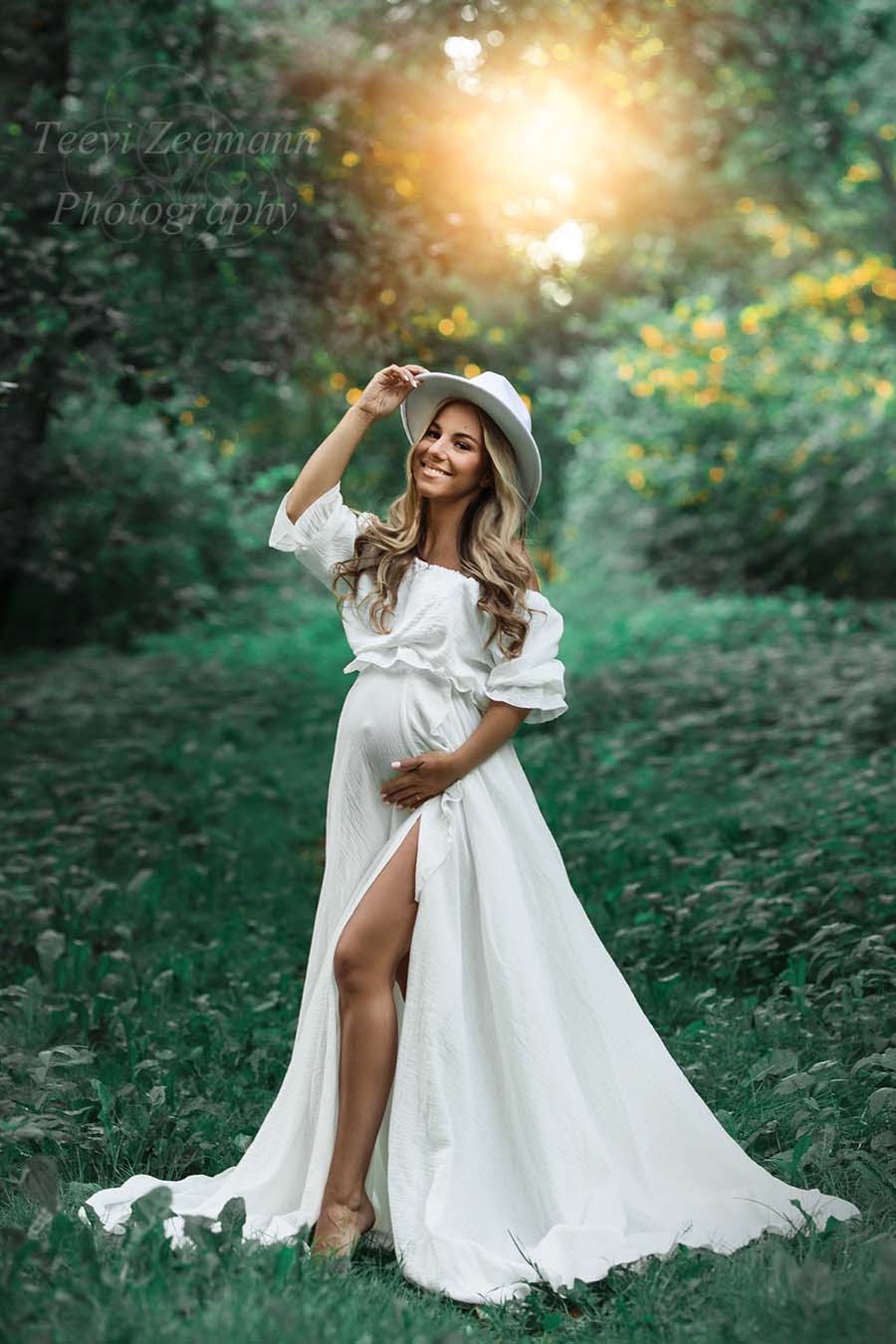 Blond model poses outside wearing an off white bohemian dress with a hat to match the look. 