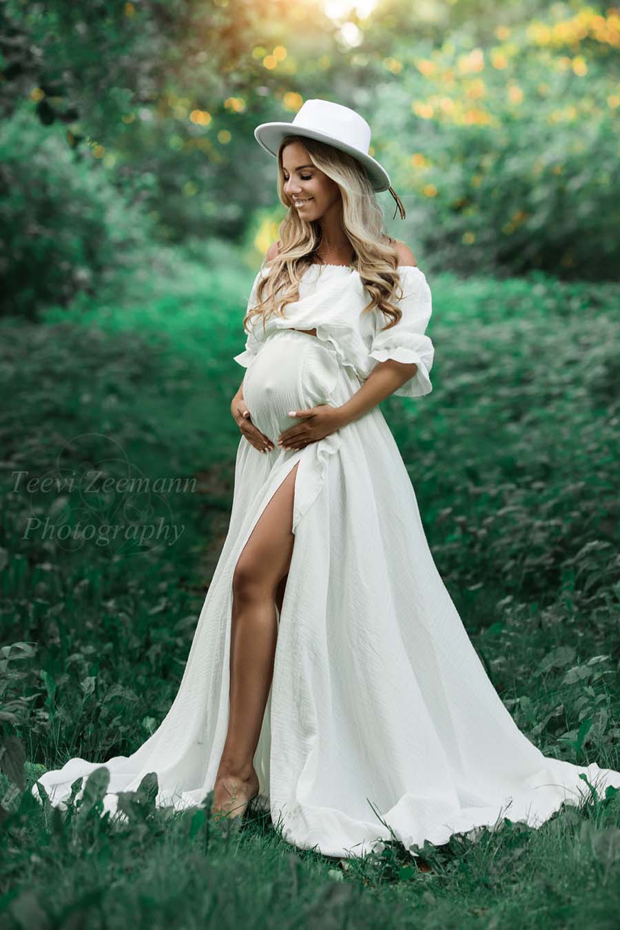 Blond model poses outside wearing an off white bohemian dress with a hat to match the look.