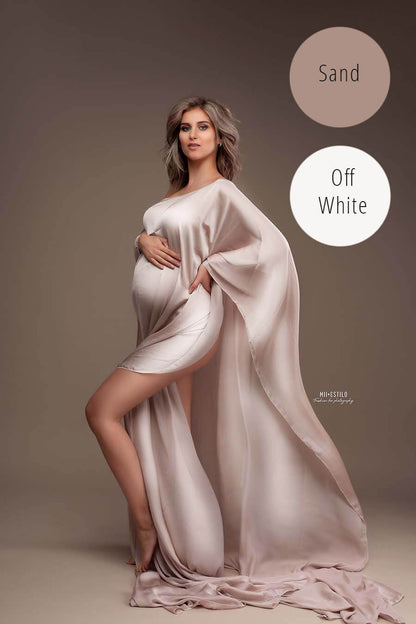 pregnant model poses in a studio wearing a silky cape in sand color. 