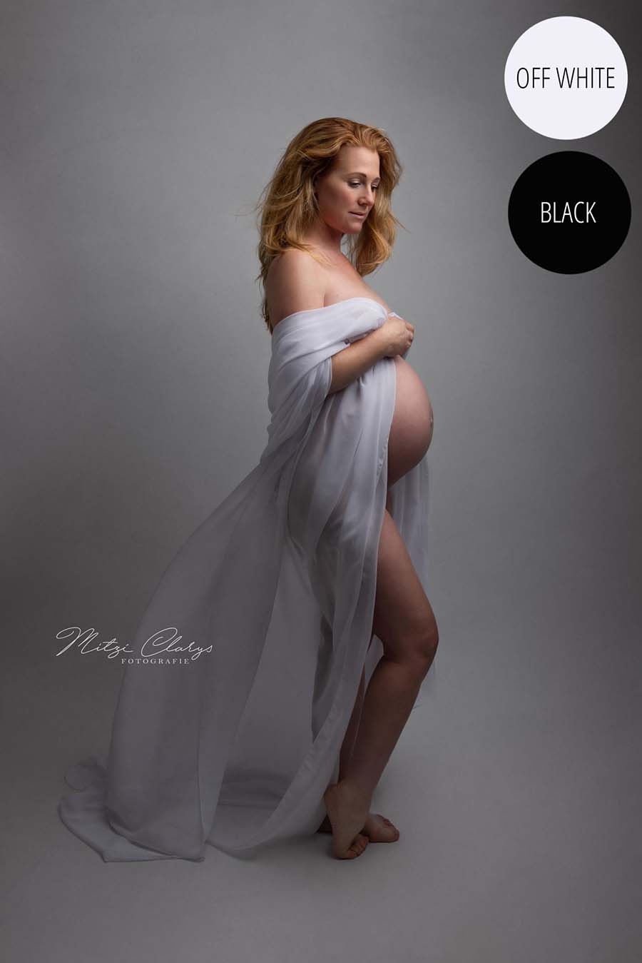 Blong pregnant model poses in a studio wearing a draping fabric made of chiffon in off white color around her arms. She looks to the side and her belly is uncovered. 