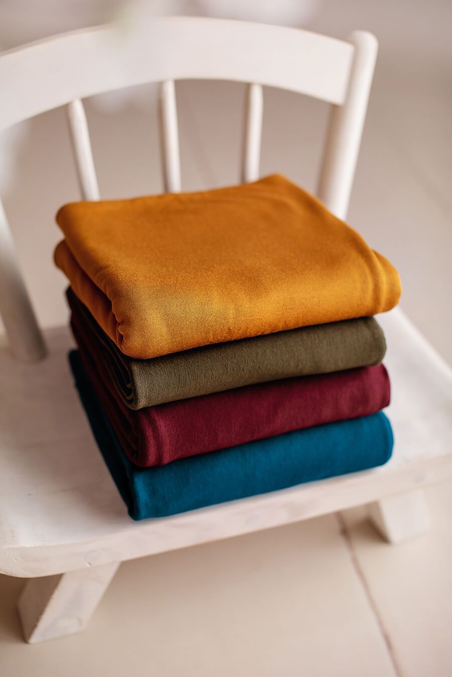 4 backdrops with different colors displayed in a studio. they are cognac, olive, bordeaux and petrol. 