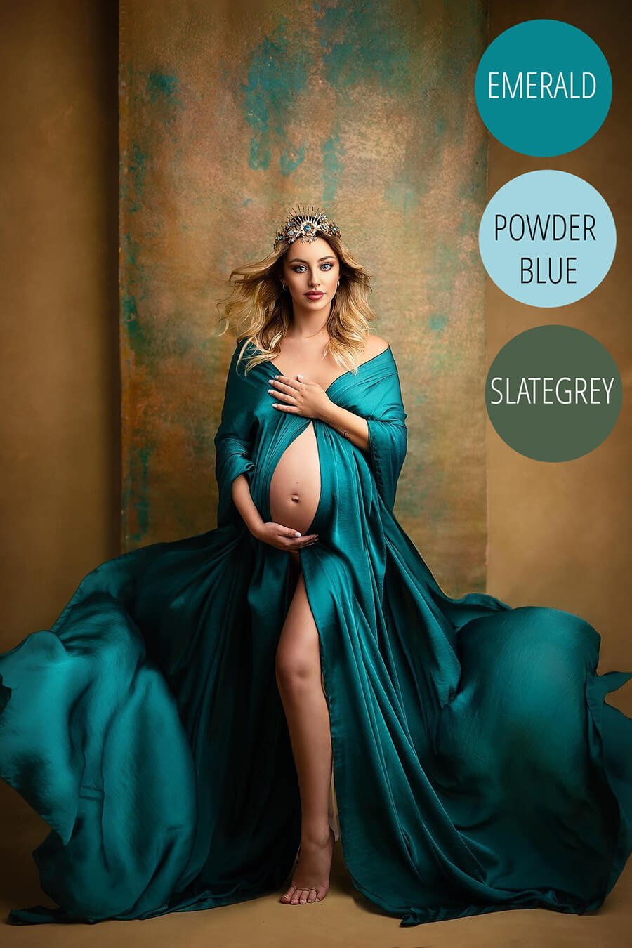 blond pregnant model poses in a studio wearing an emerald cape. she has a crown to match the style.