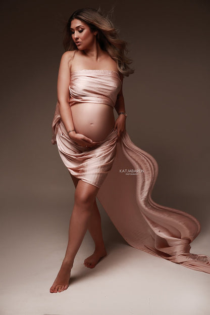 model poses wearing a dusty pink scarf covering part of her body. 