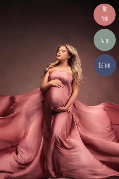 blond pregnant model poses for a maternity photoshoot wearing an old pink draping fabric to cover her body.