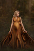 blond pregnant model poses outdoors wearing a long camel dress made of silk. 
