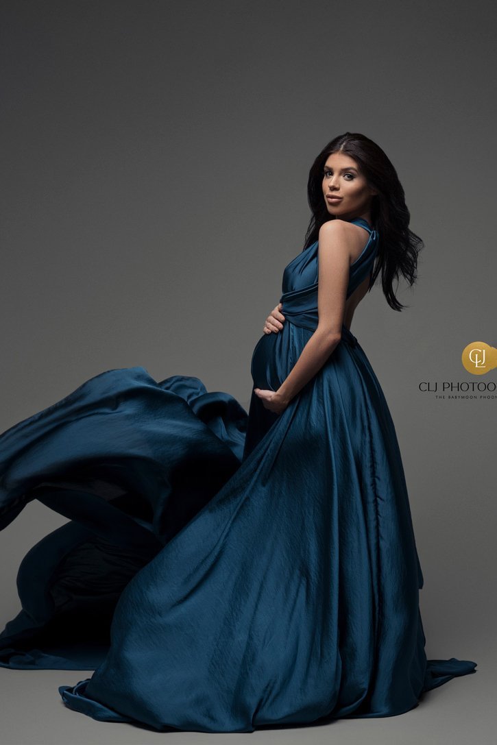 The dress that the model is wearing is thrown in the air. The model is pregnant and has long black hair