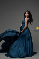 The dress that the model is wearing is thrown in the air. The model is pregnant and has long black hair