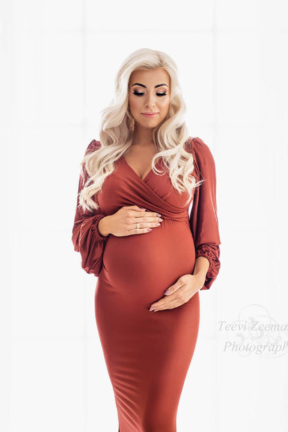 A pregnant model is wearing a long tight dress in the colour orange. She is holding her belly 