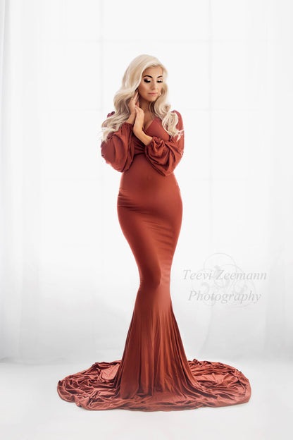 A pregnant woman is wearing a long tight dress with a mermaid skirt. She is looking down