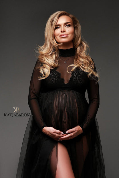 a woman with blonde hair is wearing a black dress. The dress is see trough and made from mesh fabric. The dress has a high turtle neck