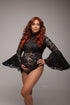 A pregnant model with red hair is wearing a black bodysuit. The bodysuit is see trough because it is made form lace. The end of the sleeves are flaired