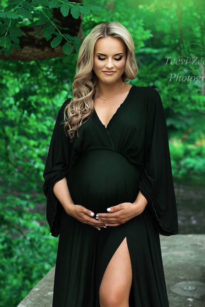 A close up photo of a pregnant woman wearing a dark green dress. The dress has a V- Neckline and wide sleeves.