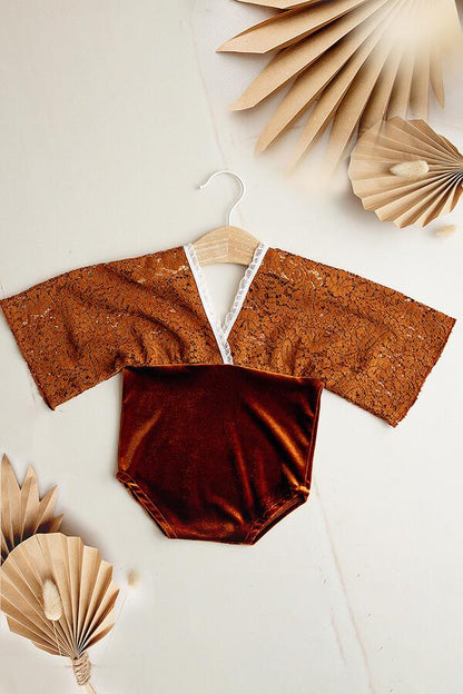 This is a product photo of the Linden Newborn Romper in the color Cognac. The romper has two materials. One is lace and the other is velours.