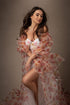 brunette model smiles during her glamour photoshoot. she is wearing a flower patterned dress made of tulle and organza.
