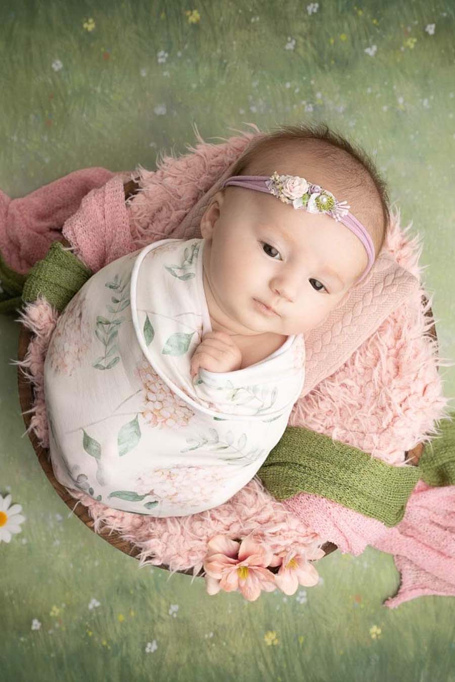 baby posing in a newborn photoshoot wrapped with a flower pattern wrap.