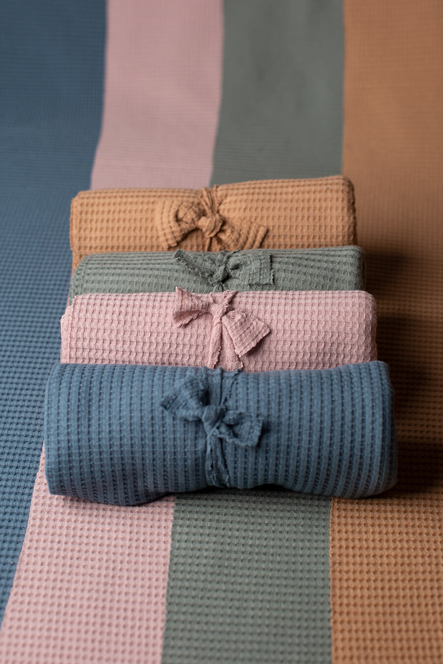 display photo of newborn wraps bundled together. the colors displayed are azur, denim, dusty muave and camel.
