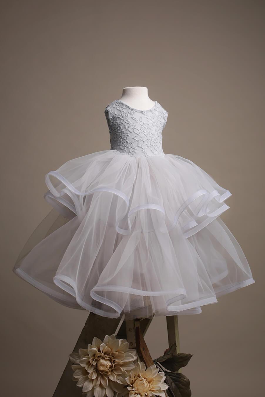 A photo of a kids dress. The top of the dress is from lace and jersey. The skirt is tulle. The dress is in the colour grey
