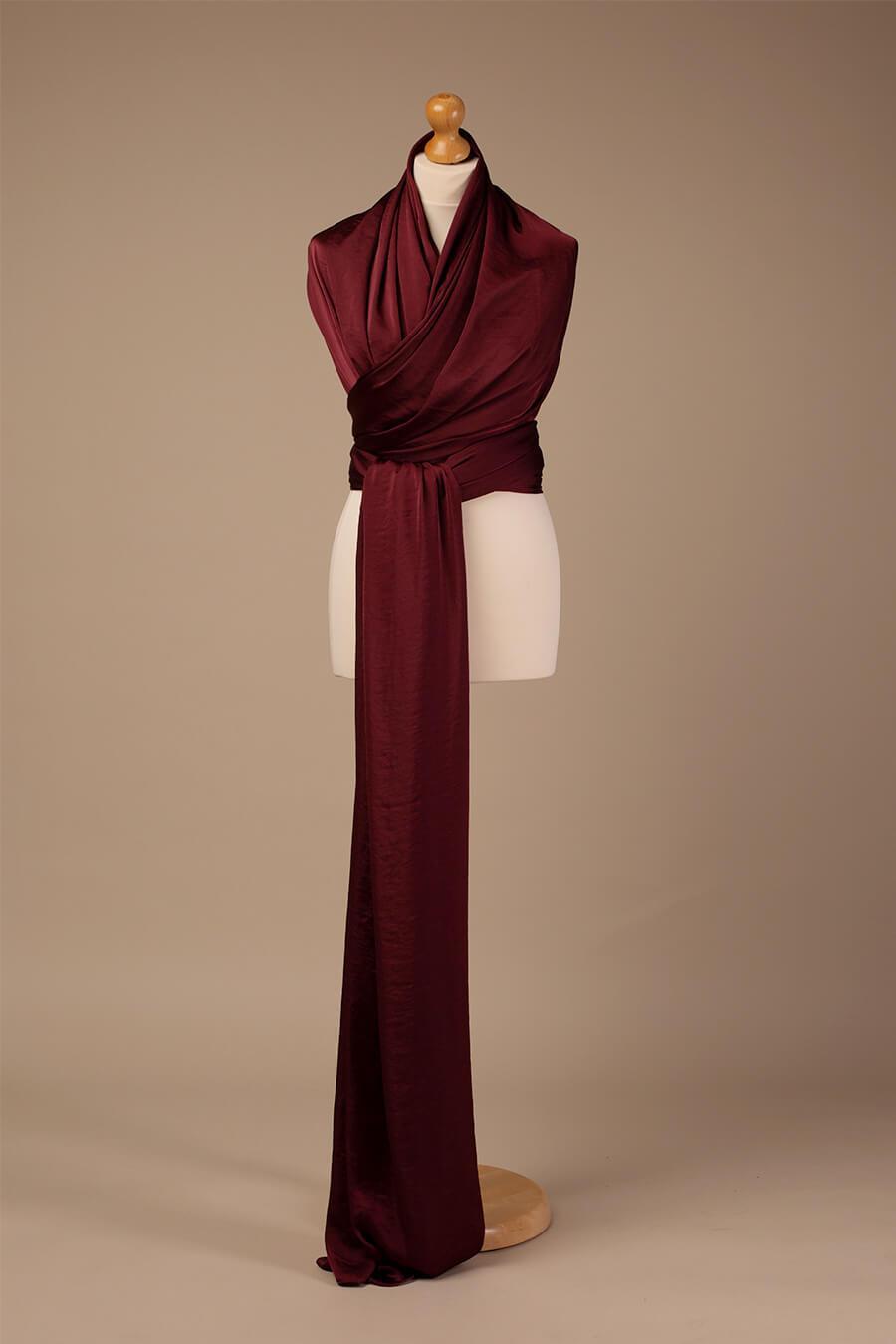 A stand with a silky scarf bordeaux wrapped around it like a dress