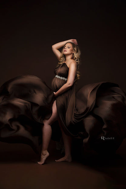 The model is wrapped in a silky fabric, She is pregnant. she is wearing a sash right under her breast 
