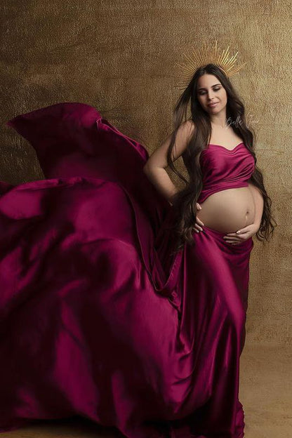 A pregnant model is wearing a silky scarf cherry. The scarf is tied into a two piece set of a crop top and a skirt. She is wearing a golden hairband on her head.