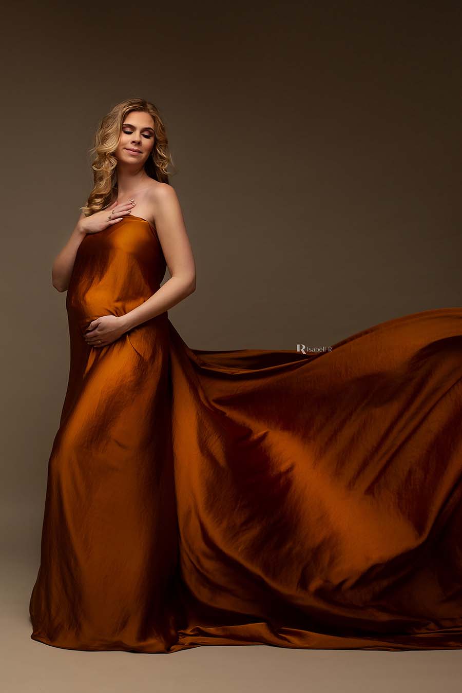 blond model covers her breast and belly with a cognac scarf. she has her eyes closed and one of her hands resting on her chest.