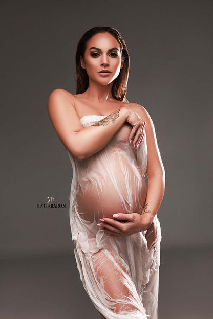 pregnant model poses with a white wet silky scarf covering her body.