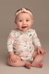 baby poses wearing a romper with long sleeves and flower pattern. she has a matching hairband.