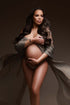 Pregnant model poses during her maternity photoshoot wearing a draping fabric made of voile in taupe color. she cover her breasts with the scarf and has her belly uncovered. She looks to the side during the close up. 